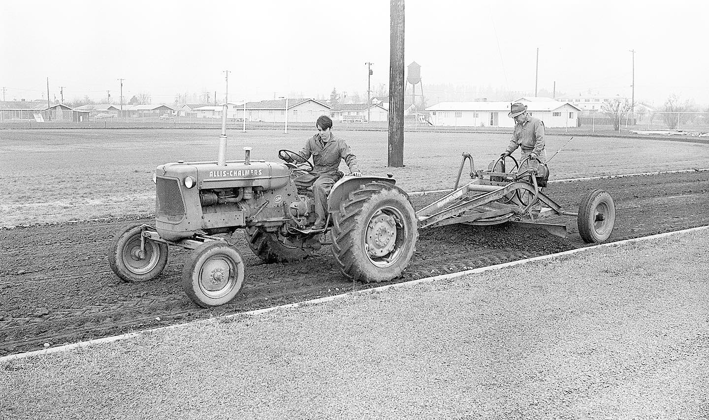 2 men on tractor and leveler.